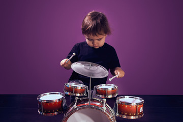Happy young child playing drums color background