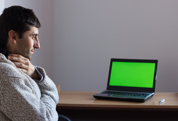 Young man sick at home by green screen laptop. Ill person with hand on mouth sitting by computer desk at home