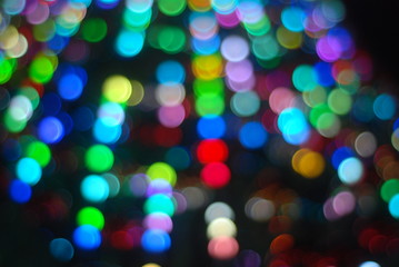 Defocused Glare from the Christmas tree garlands, against the night sky, a festive background.