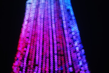 Defocused Glare from the Christmas tree garlands, against the night sky, a festive background.