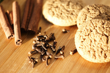 Fototapeta premium several pieces of oatmeal cookies, clove spice and cinnamon sticks lie on a sunlit cutting Board