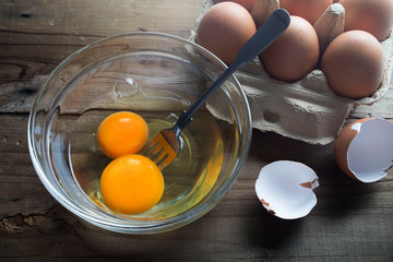 Raw eggs in a glass bowl and chicken eggs in box on the table.