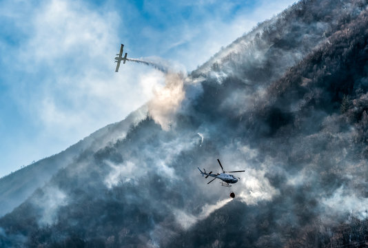 Firefighting Aircraft and Helicopter dropping the water for fighting a fire on mountain, above Lake Ghirla in Valganna, province of Varese, Italy