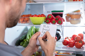 Person's Writing On Diary Near Refrigerator