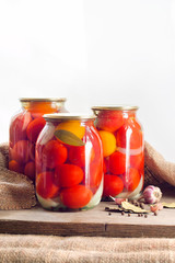 Glass jars with red pickled tomatoes, sealed with metal lid