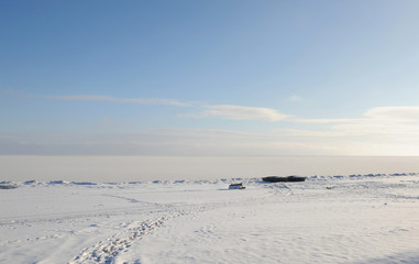 Fototapeta na wymiar Winter snowy coastal landscape on a sunny day. Frozen river. Clear sky. Open space. Two boats on the shore