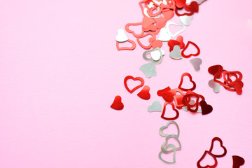 Silver and red shiny design hearts on pink neutral background with empty space for image or text. Confetti for romantic happy valentines day. holiday hearts made of silver paper. 