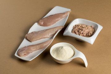 Raw chicken Breasts, tuna in oil and a whey protein scoop vanilla flavor. Sport nutrition. Brown table