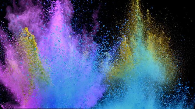 Super slowmotion shot of color powder explosions isolated on black background.