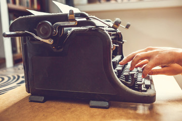woman hands type on an old vintage dust-covered typewriter