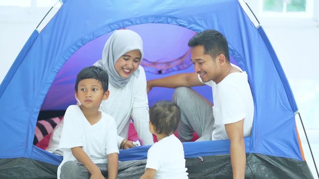 Happy family playing together while sitting inside a camping tent. Shot in 4k resolution