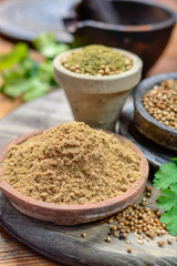 Clay bowls wirh dried coriander seeds and coriander powder close up, spices collection