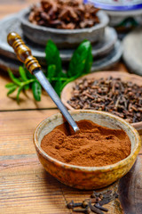 Bowls with dried clove buds and cloves powder, used for cooking and traditional medicine, close up, spices collection
