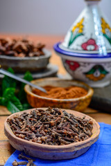 Bowls with dried clove buds and cloves powder, used for cooking and traditional medicine, close up, spices collection