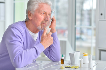 Sick senior man with pills posing at home