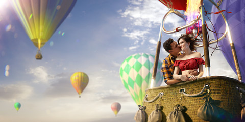 Young beautiful multiethnic couple kissing in the hot air balloon. Very romantic picrure