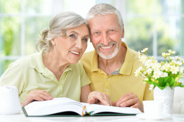 Portrait of happy senior couple with book drinking tea