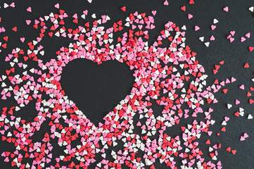valentine heart on a black slate background with tiny heart sprinkles