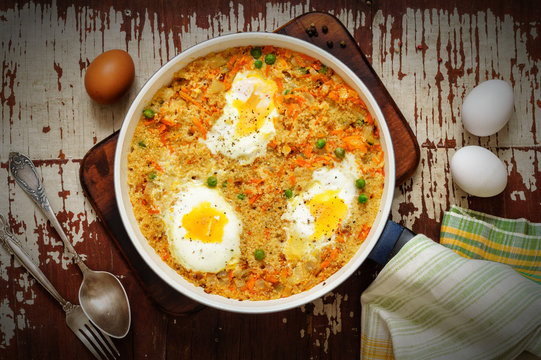 Wheat porridge with vegetables and eggs in a white pan