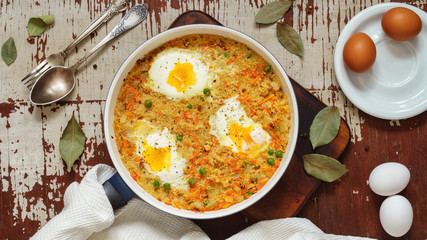 Wheat porridge with vegetables and eggs in a white pan