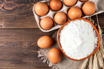 Flour and eggs on dark wooden table. Baking background.