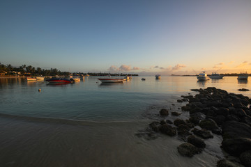Sunset on the beach of the island of Mauritius where yachts float on water and boats