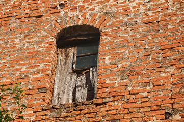 Grunge broken  window of old rural weathered neglected abandoned house red brick wall closeup