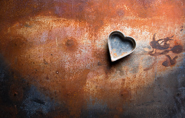 Kitchen mold in the shape of a heart on a rustic background.