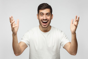 Fototapeta premium Young happy crazy man showing big size gesture with hands, emphasizing great amount of something