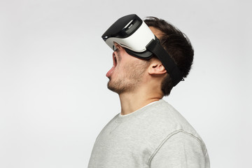 Shocked young man watching horror movie though VR glasses, screaming
