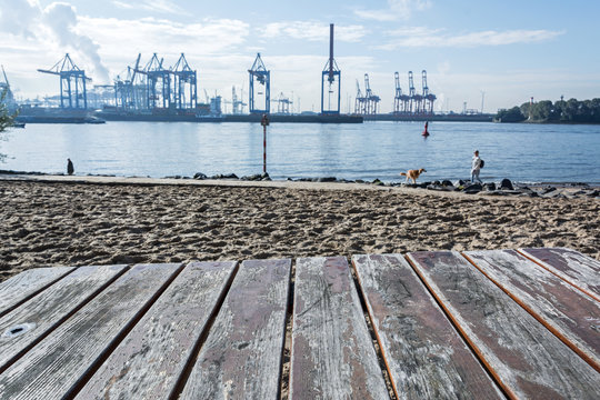 Tisch am Elbstrand mit Hafenkr&auml;nen im Hintergrund in Hamburg