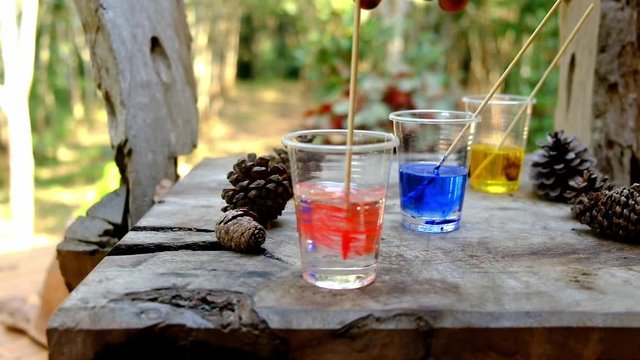 Mixing epoxy resin red color in cup for casting Stabilizing wood and pine cone hybrid