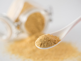 Nutritional yeast background. Nutritional inactive yeast in small spoon and spilled from glass jar...