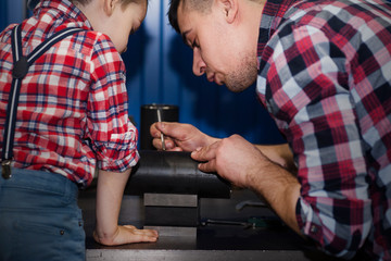 good father took his little son to work with metal. Concept of relationship, child at work turner