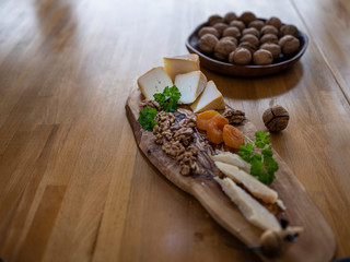 Some peaces of the french cheese Petit Bonet together with soft apricot, nuts and parsley on the olive desk