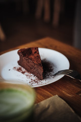 One slice of vegan chocolate brownie cake on wooden table. Sugar free, wheat free, dairy free, flourless dessert. Dark mood food photo. Healthy eating, lifestyle concept. Copy space