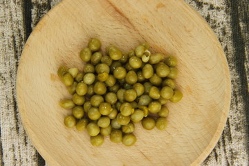 Petits pois sur une assiette en bois