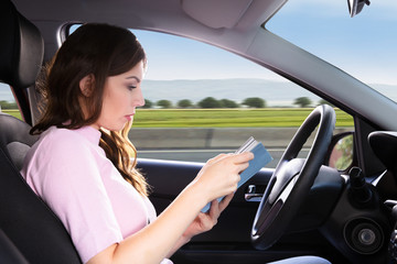 Obraz na płótnie Canvas Woman Reading Book While Driving Car