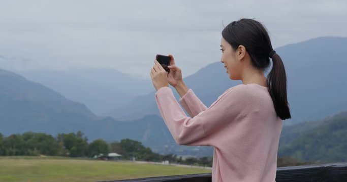 Woman take photo on cellphone with beautiful scenery view