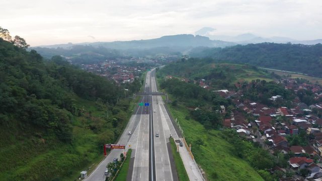 Semarang, Central Java / Indonesia - January 11, 2019: Aerial scenery of Trans-Java Toll Road with residential houses and tropical hills background. Shot in 4k resolution