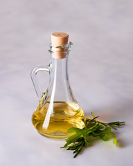 a bottle of olive oil and a sprig of olives on a marble background