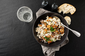 Risotto with  champignons mushrooms on black stone background .
