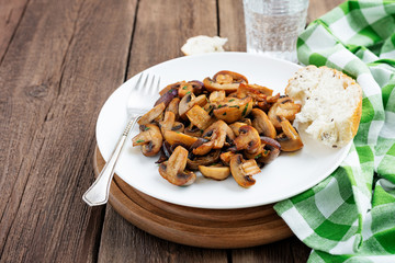Fried mushrooms with fresh herbs in white plate .