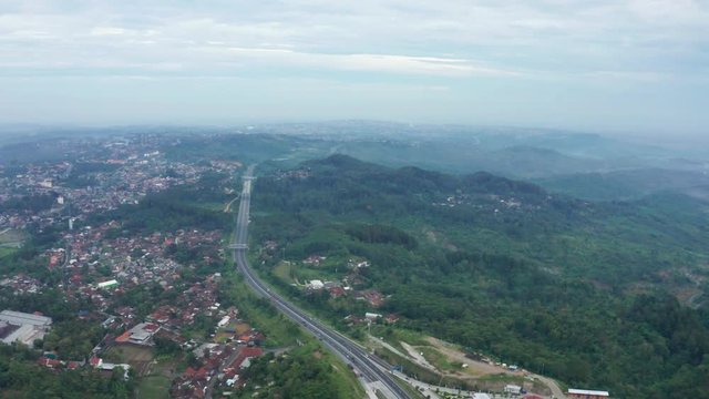 Beautiful aerial view of residential houses and tropical forest near Trans-Java Toll Road at Ungaran from Semarang to Solo, Central Java, Indonesia. Shot in 4k resolution
