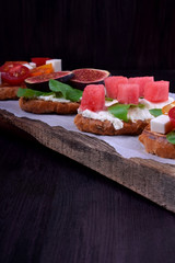 Assortment of bruschettas with figs, watermelon, cherry tomatoes, cheese and honey