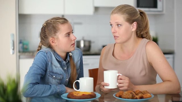 Mother and her teenage daughter having emotional dialog in kitchen