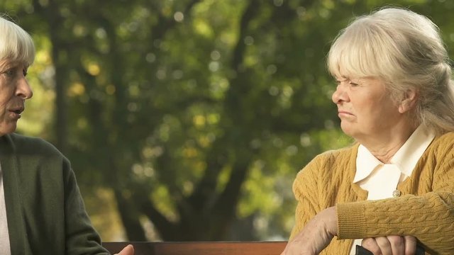 Grumpy mature women talking sitting on bench, old age negativity, conversation