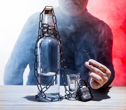 a man has secured a bottle with alcohol and a shot glass with a chain and padlock