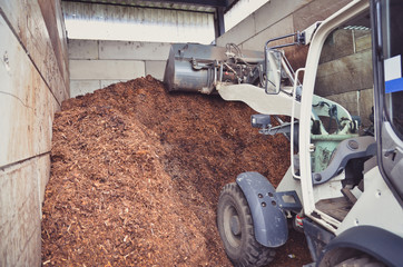Wheel loader is working with a fertilizer storage as a result of organic wastes recycling process on a biogas plant.