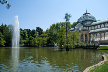 Fototapeta na wymiar Famous Crystal Palace or Palacio De Cristal in Buen Retiro Park near pond. Madrid, Spain